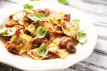 Ravioli with mushrooms and fresh basil. Bright wooden background. Close up.	
