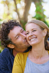 Fototapeta premium Happy, couple and kiss outdoor for love and bonding, trust and support in commitment for marriage. Partner, loyalty and joy with people in nature for fresh air, date and affection in relationship