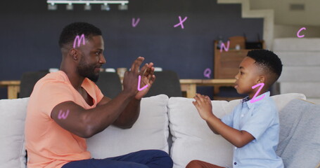 Image of letters over happy african american father and son playing finger games