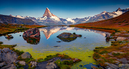 Calm dawn on Stellisee lake. Spectacular summer sunrise in Swis Alps with Matterhorn peak on...