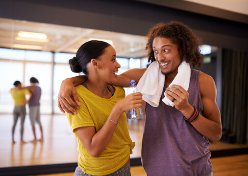 People, drinking water and relax in dance studio, smile and break from practice or learning technique. Partners, happy and laugh for humor in training, hydration and nutrition for exercise or workout