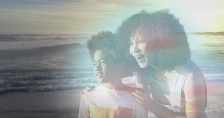 Image of happy african american mother and son at beach on sunny day smiling over sea