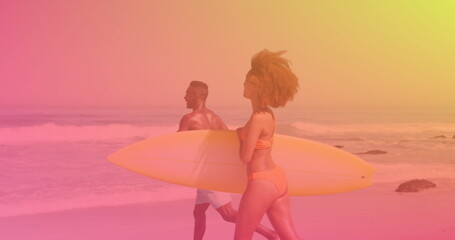 Fototapeta premium Image of happy couple at beach on sunny day carrying surfboards over colourful light