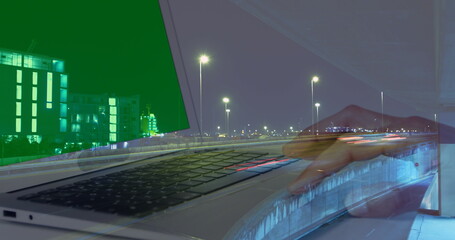 Image of hands of woman using laptop with green screen over sped up traffic in city at night