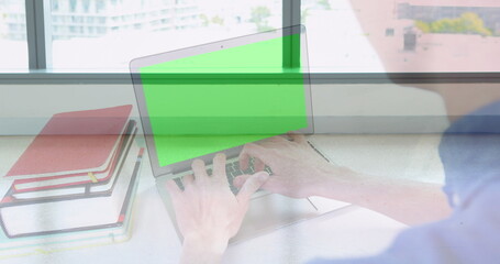 Image of hands using laptop with green screen over colleagues walking in modern building