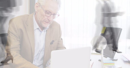 Image of businessman using laptop over sped up commuters walking in building