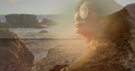 Fototapeta premium Image of african american woman in sunglasses over sunny landscape