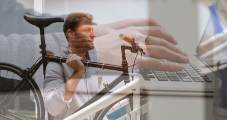 Image of hands using laptop over businessman climbing stairs carrying bike