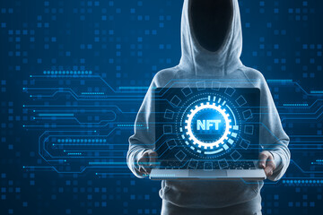 Hacker in hoodie holding laptop with creative round nft hologram on digital blue background....