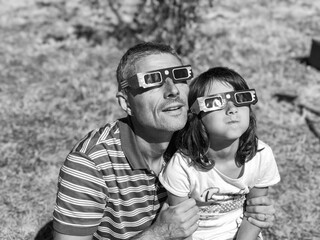 Father and daughter looking at the sun during a solar eclipse on a country park, family outdoor activity - 756986155