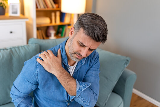 Young man with shoulder pain. male holding his painful shoulder. man hand holding his shoulder suffering from shoulder pain suffering from pain in hand at home.