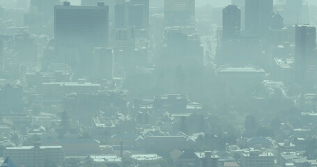 A cityscape is obscured by a thick layer of smog, signaling pollution issues