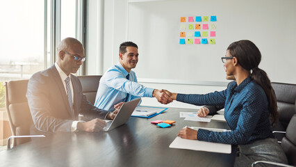 An african american business woman and a businessman shaking hands during a meeting in an office, as an end to which they have entered into a cooperation agreement with their teams - 756994317