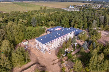 construction of a multi-storey building, hotel or sanatorium clinic in the middle of a forest from a bird's eye view - obrazy, fototapety, plakaty