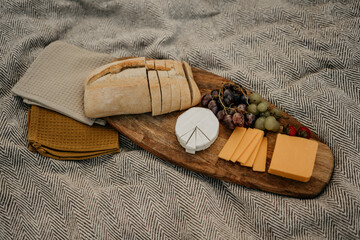 Weintrauben, mit Baguette und Käse auf einem Holzbrett für ein Picknick