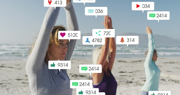 Image of social media notifications, over women doing yoga on beach
