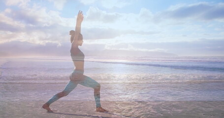 Fototapeta premium Side view of a woman doing yoga on the beach on a sunny day