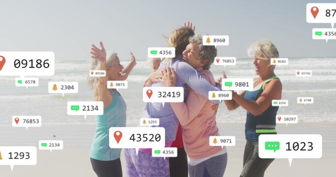 Image of social media notifications, over women exercising embracing on beach - Powered by Adobe