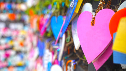 Colorful hearts hanging on wall on the street. Love pink heart shape on blur bokeh background. Copy...