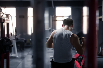 The yellow man is exercising his arm muscles in the gym