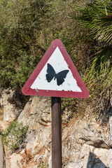 triangular traffic sign with the drawing of a butterfly inside it
