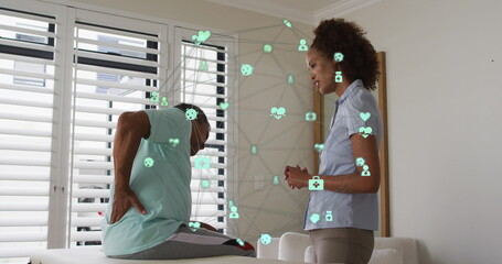 Image of connections over africna american female doctor and patient with back pain - Powered by Adobe