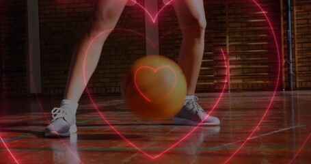 Image of neon hearts over caucasian female basketball player bouncing ball