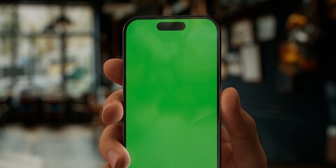 Person holding a smartphone with a green screen in a blurred cafe setting - 757015570