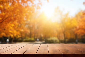 Naklejka na ściany i meble Autumn maple trees bokeh background with shiny sunlight empty brown wooden table for display