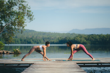 Beautiful attractive Asian woman practice fitness yoga pose on the pool above the Mountain peak in front of nature lake views, Feel so comfortable lifestyle and relax exercise in holiday morning