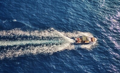 Top view of a fishing vessel going through
water living backwash in calm blue waters 
