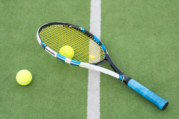 Tennis racket and tennis ball besides the net on outdoor tennis court.