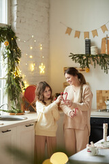 Mom and daughter celebrate the new year together, laugh, collect a heart of sweets against the background of a homely cozy atmosphere