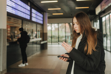 Tourist teenage girl at train station using smartphone map, social media check-in, or buy ticket booking. Modern travel app technology, lone traveler, Winter vacation railroad adventure concept - 757023577