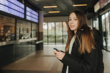 Tourist teenage girl at train station using smartphone map, social media check-in, or buy ticket booking. Modern travel app technology, lone traveler, Winter vacation railroad adventure concept - 757023709