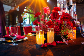 Beautiful festive table setting with fresh red flowers, napkins and candles. 