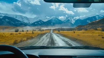 Photo sur Plexiglas Voitures de dessin animé An aerial view of the landscape through the windshield of a car going across a meadow to high rocky mountains in different seasons with varying weather. The “natural landscape” is viewed from inside
