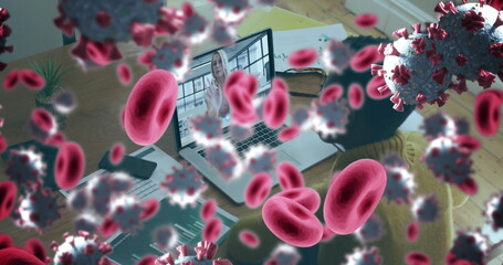 Image of covid 19 cells and red blood cells over businesswoman using laptop