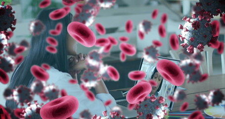 Image of covid 19 cells and red blood cells over businesswoman using laptop