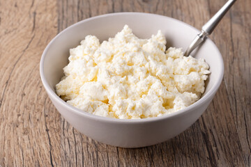 Cottage cheese in a bowl on a wooden table