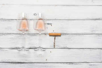 Two glasses of pink wine and a corkscrew flat lay on a white wooden background. View from above. - 757036574