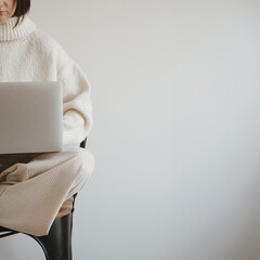 Woman works using laptop computer over white wall. Aesthetic neutral pastel beige color. Minimal...