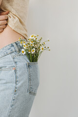 Young woman wuth chamomile flowers bouquet in jeans pocket