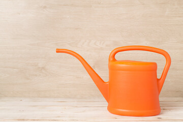 Orange watering can on wooden table
