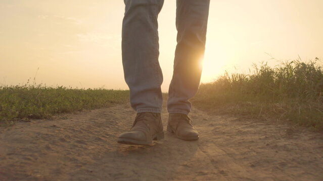Close up of a farmer's feet in boots walking along a dirt road in a rural area in a field raising clouds of dust and inspecting their property. Agricultural works to prepare the territory for the prod