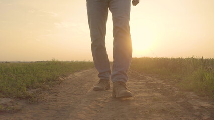 Close up of a farmer's feet in boots walking along a dirt road in a rural area in a field raising...