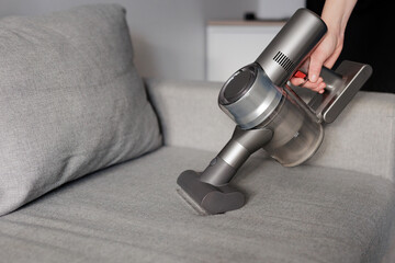 close up of female hand cleaning sofa with vacuum cleaner