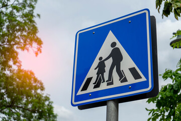 Pedestrian crossing sign on blue sky background. School zone traffic sign. Crosswalk sign. Blue zebra crossing road sign. School zone warning sign.