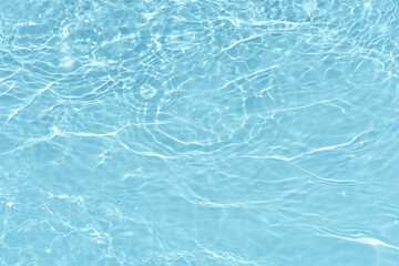 Bluewater waves on the surface ripples blurred. Defocus blurred transparent blue colored clear calm water surface texture with splash and bubbles. Water waves with shining pattern texture background.