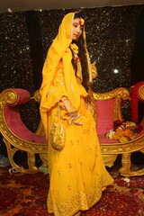 Portrait of a beautiful female model in yellow saree with light makeup and jewelry made of flowers. Its a wedding dress and makeup of Indian bride for Haldi function.